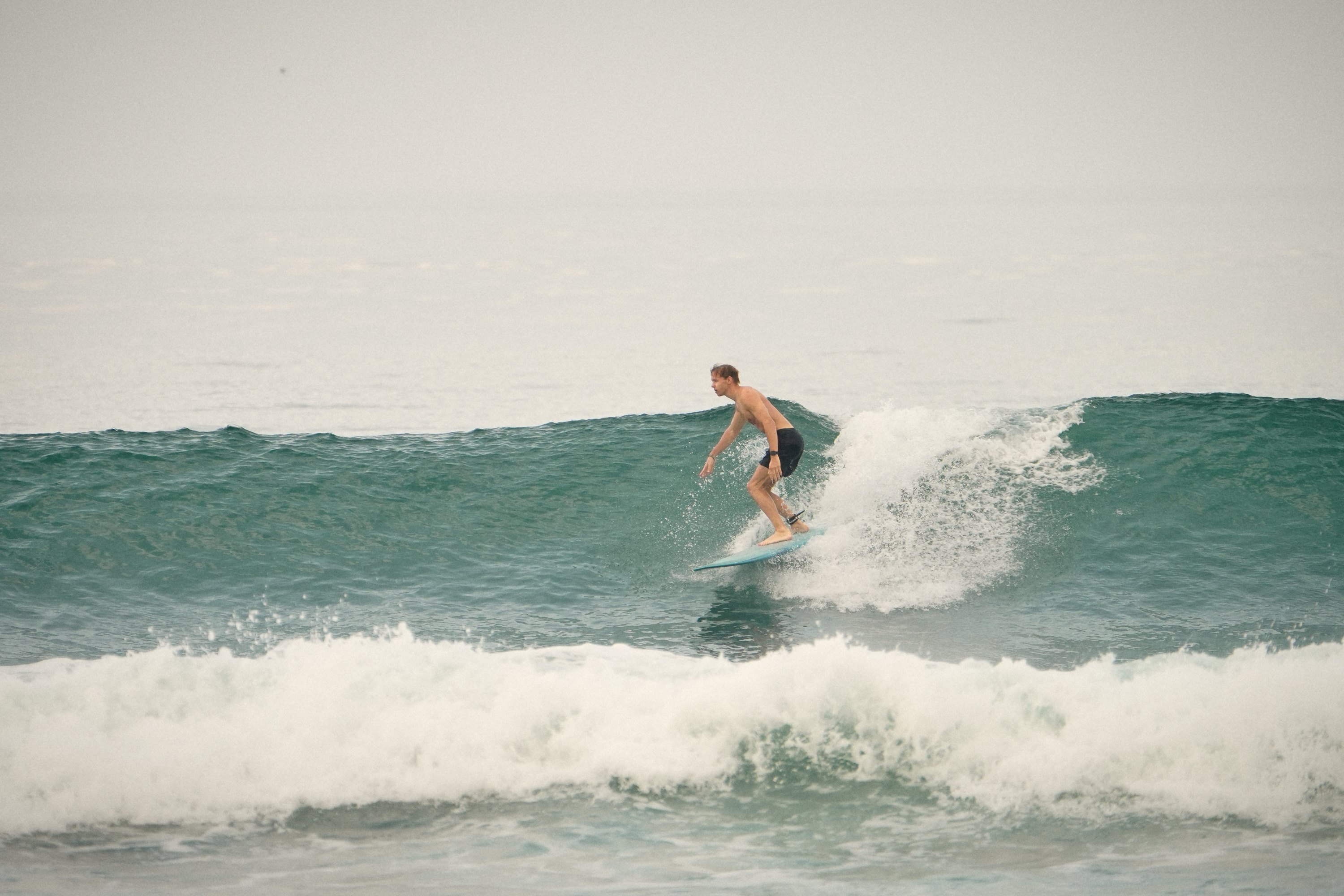 Surfer trimming across a clean green wall