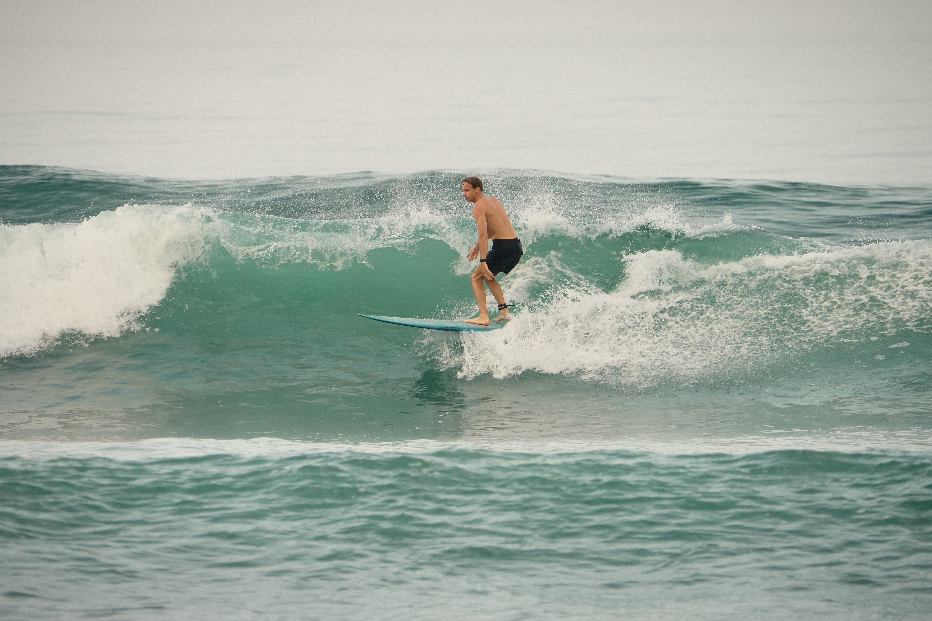 Surfer on the green face of a wave at Batu Bolong, spray behind him