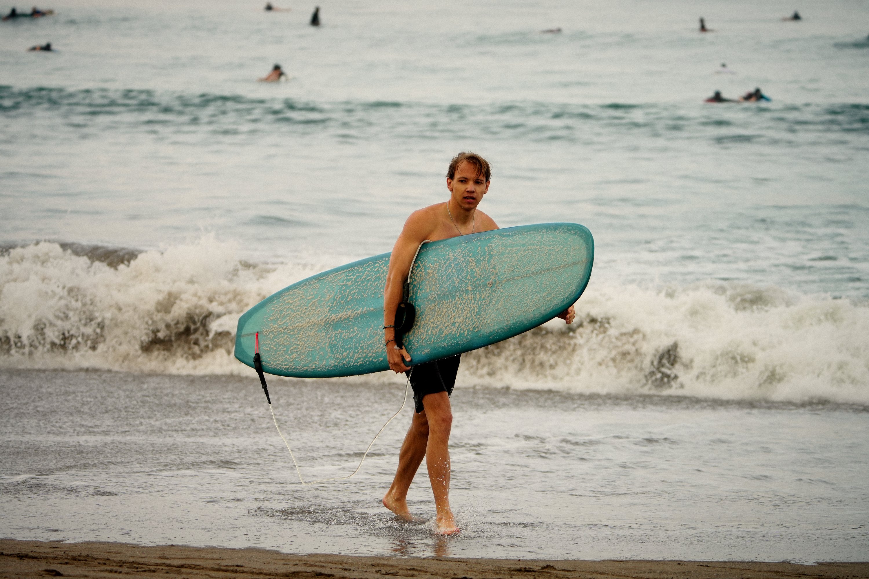 Surfer walking out of the sea with his board after the session